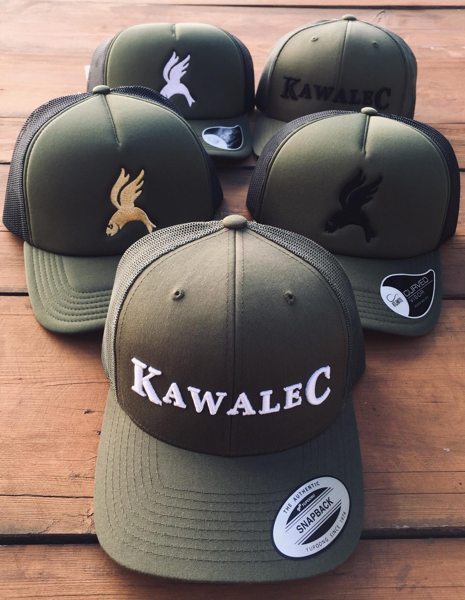 Pięć czapek KawaleC w kolorze khaki na drewnianym stole